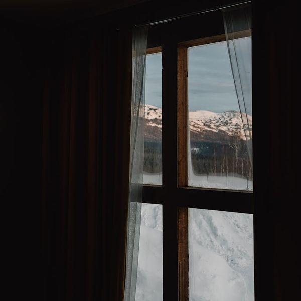 Person meditating peacefully near a large window.